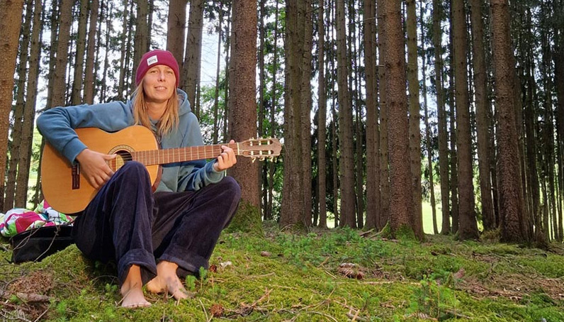 Vereinsgründerin Jenny musiziert mit ihrer Gitarre im Wald